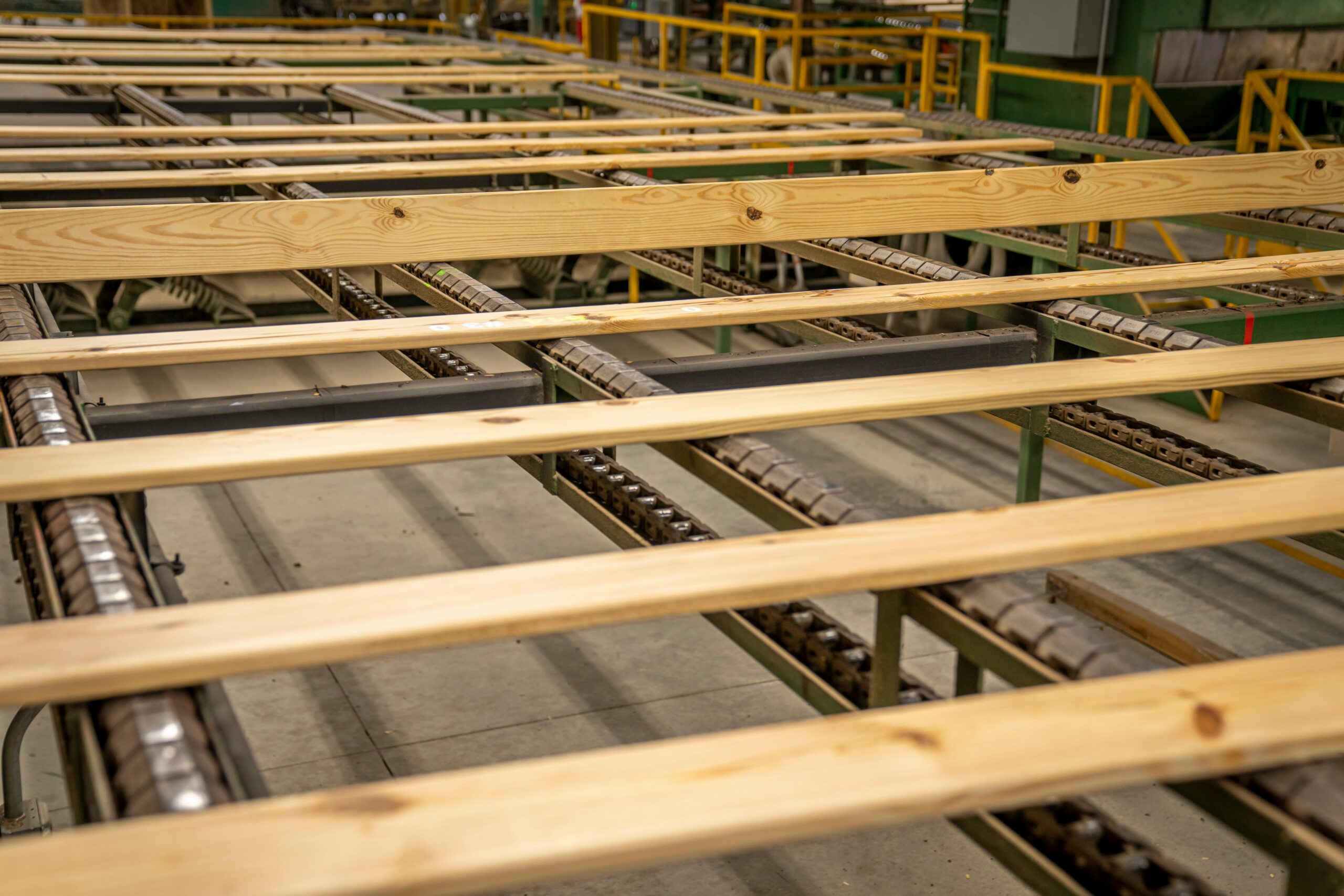 Close-up of wooden planks on a production conveyor in a factory setting.