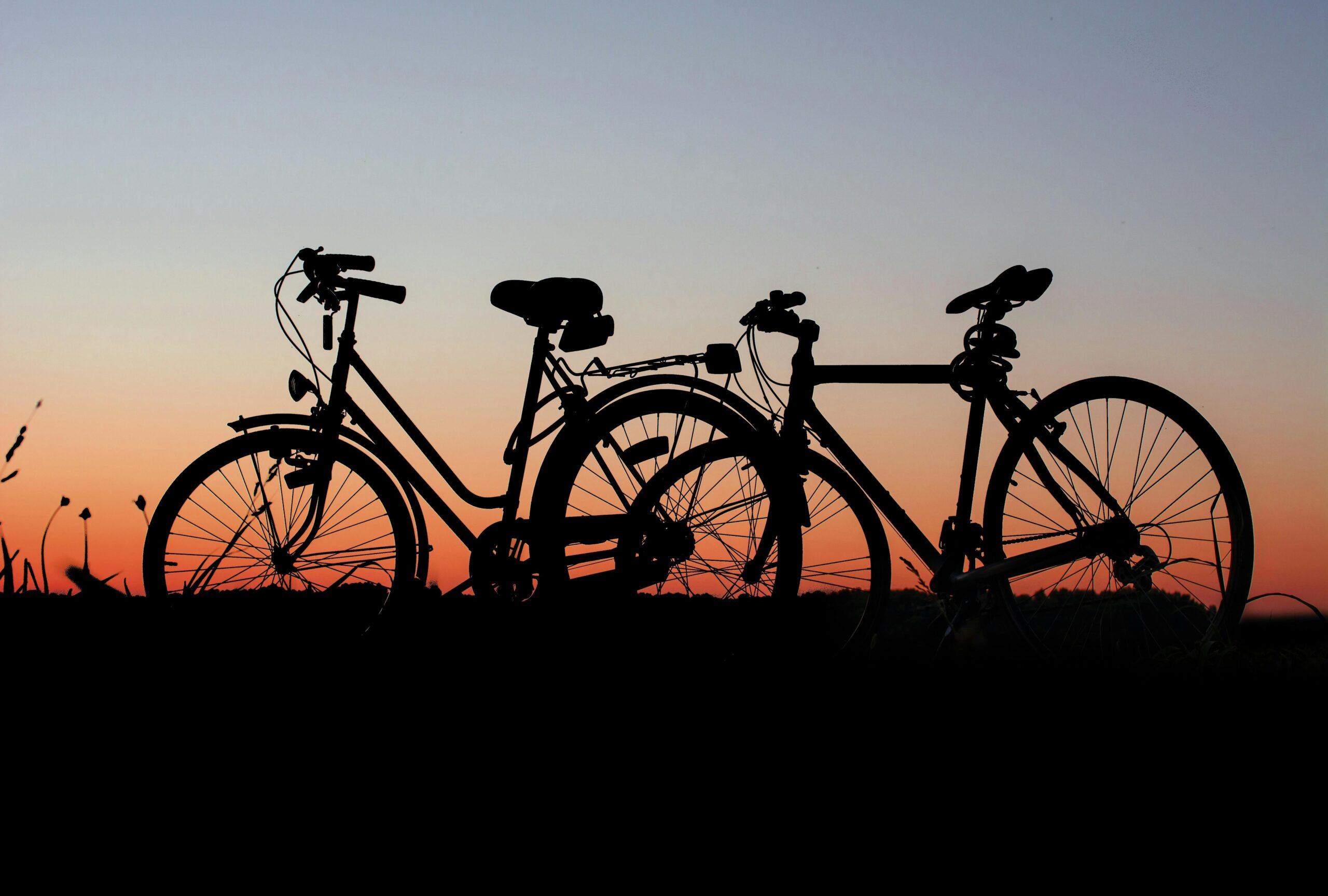Two bicycles silhouetted against a colorful sunset sky, highlighting outdoor adventure.