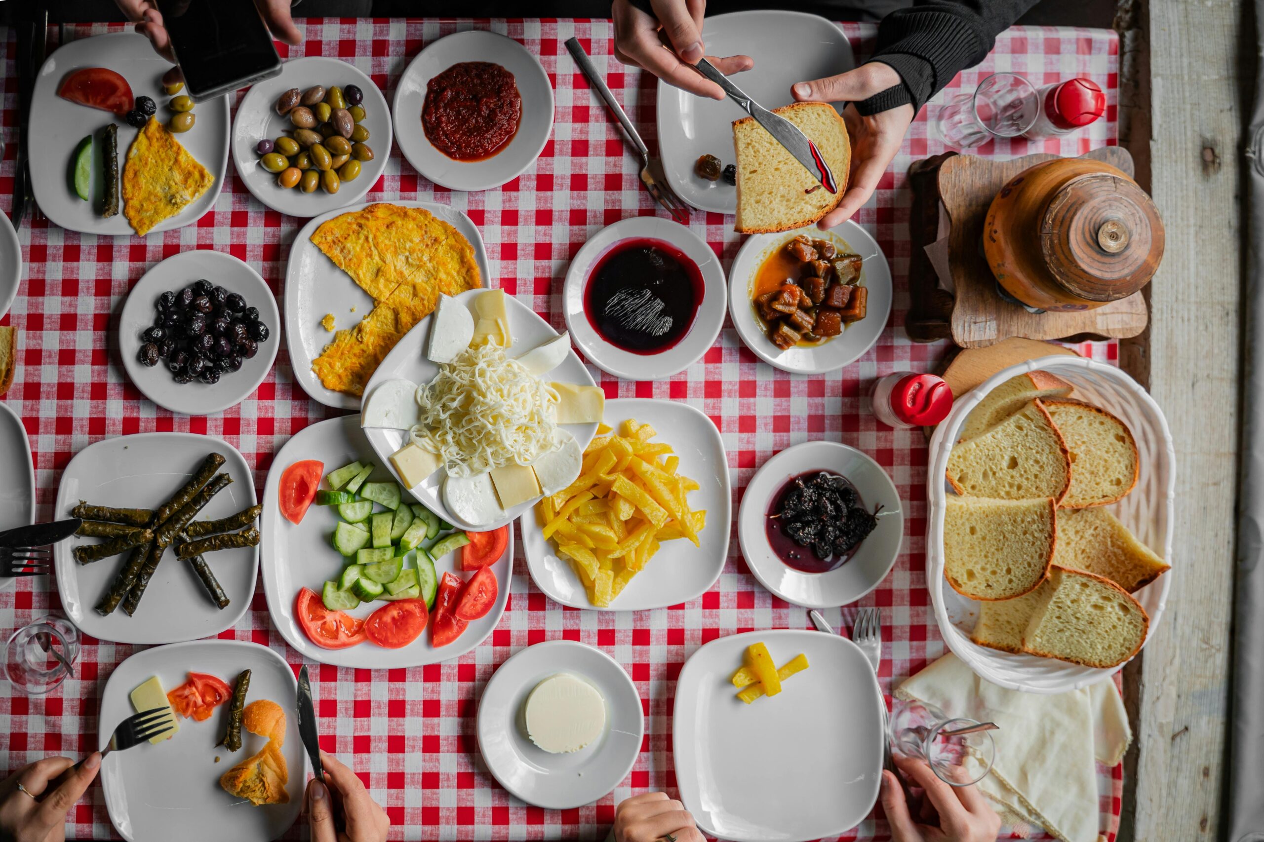 Colorful assortment of traditional Turkish breakfast dishes on a red checkered tablecloth.