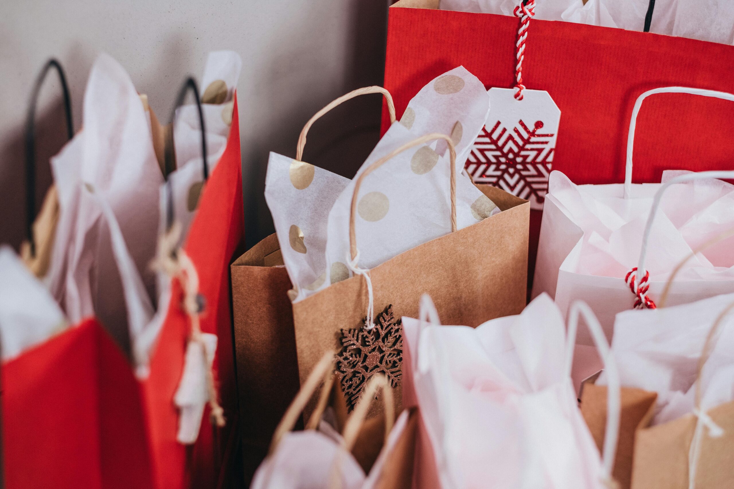 Collection of festive shopping bags filled with holiday gifts.