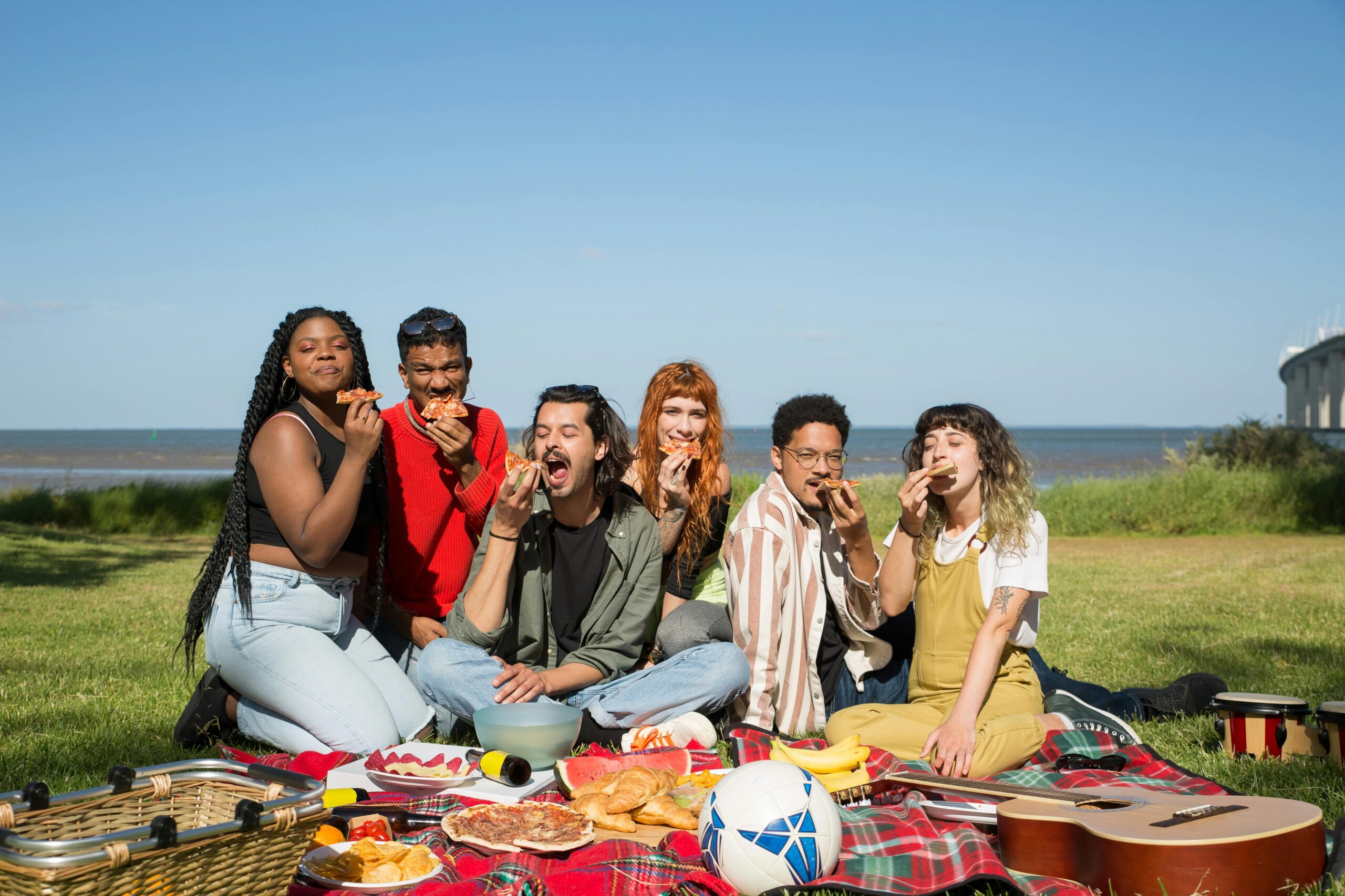 Friends enjoying a sunny picnic by the beach in Portugal, savoring food and fun.